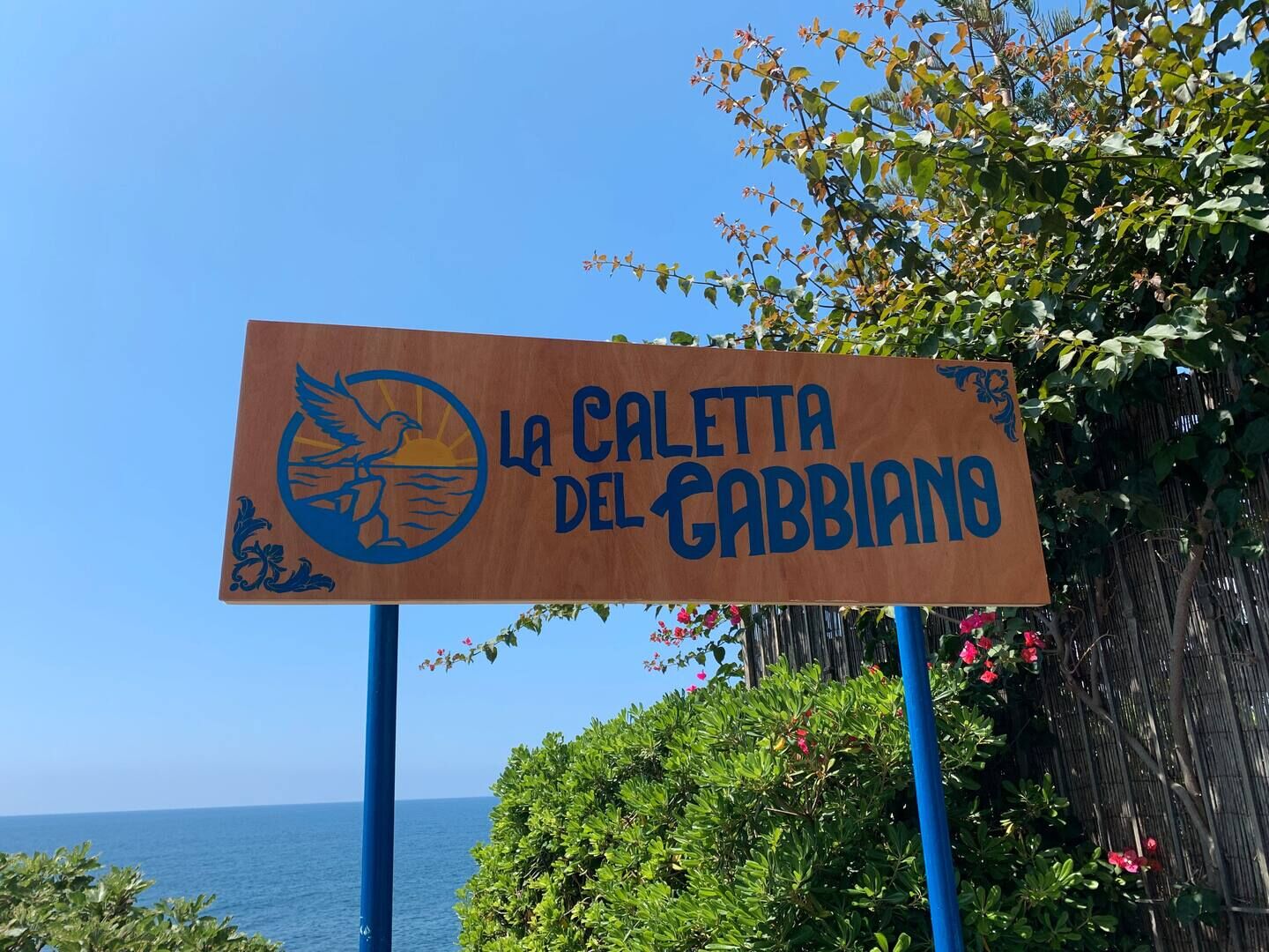 Cartello della Caletta del Gabbiano sul mare